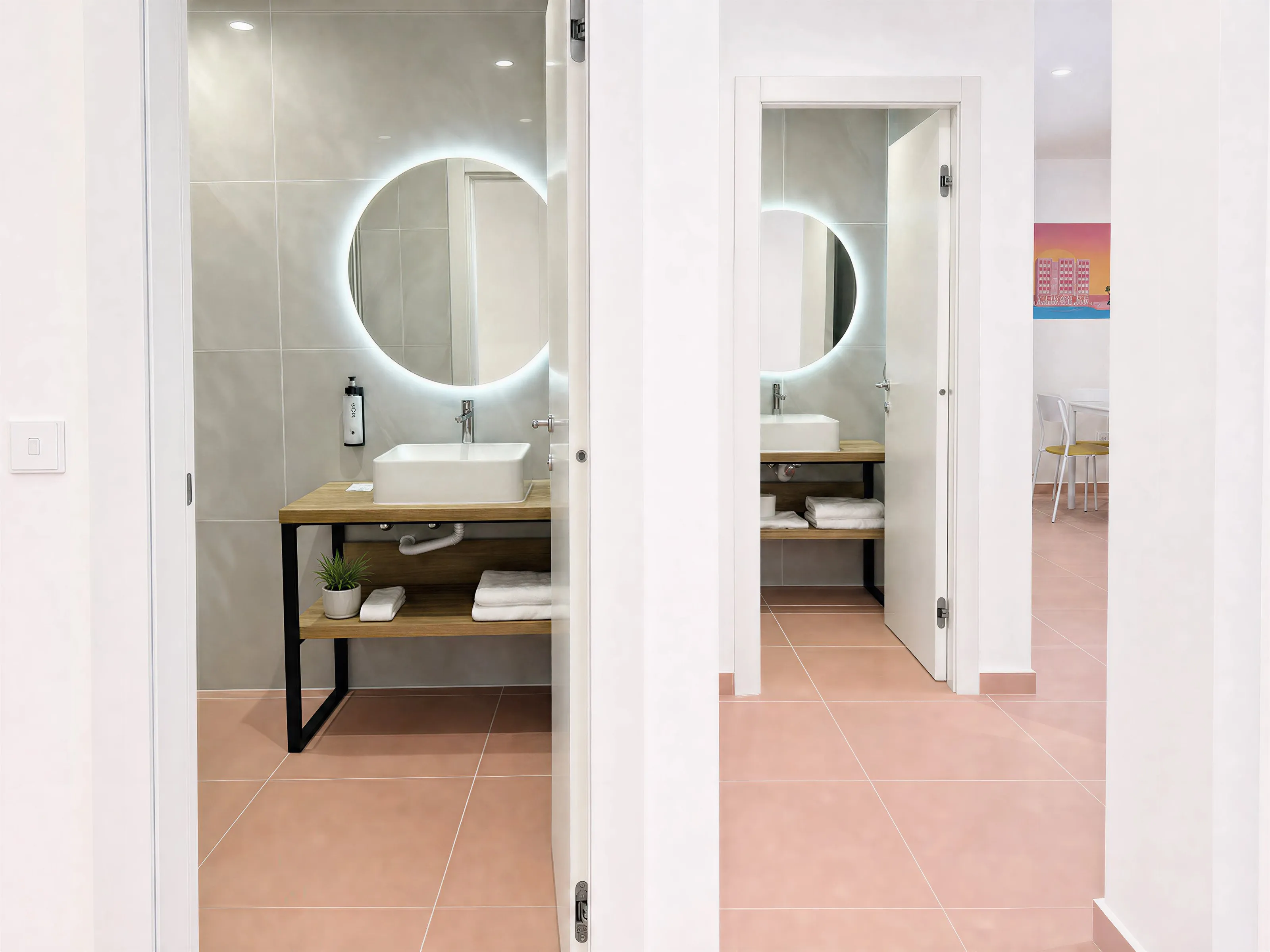 Two open bathroom doors, each with a round backlit mirror and basin