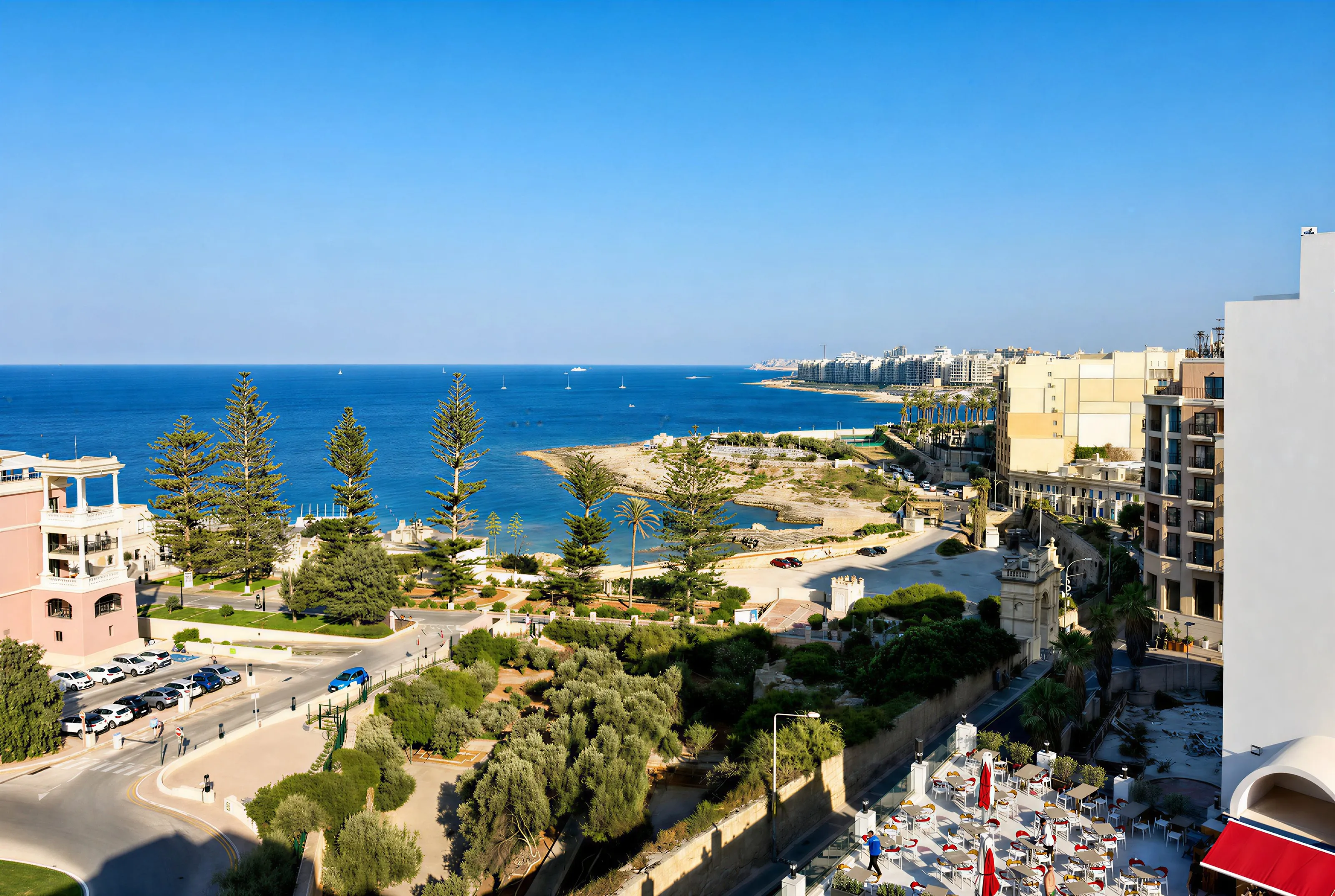 View from an upper floor over pine trees and the bay to the coastline