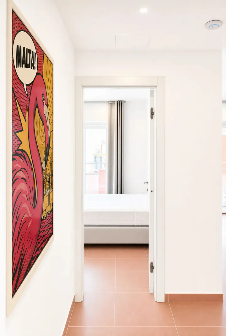 Hallway with a large 'MALTA!' flamingo pop-art print and a bedroom door