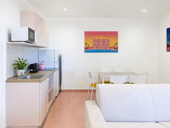 Kitchen, dining table and sofa, with a pop-art painting of the building