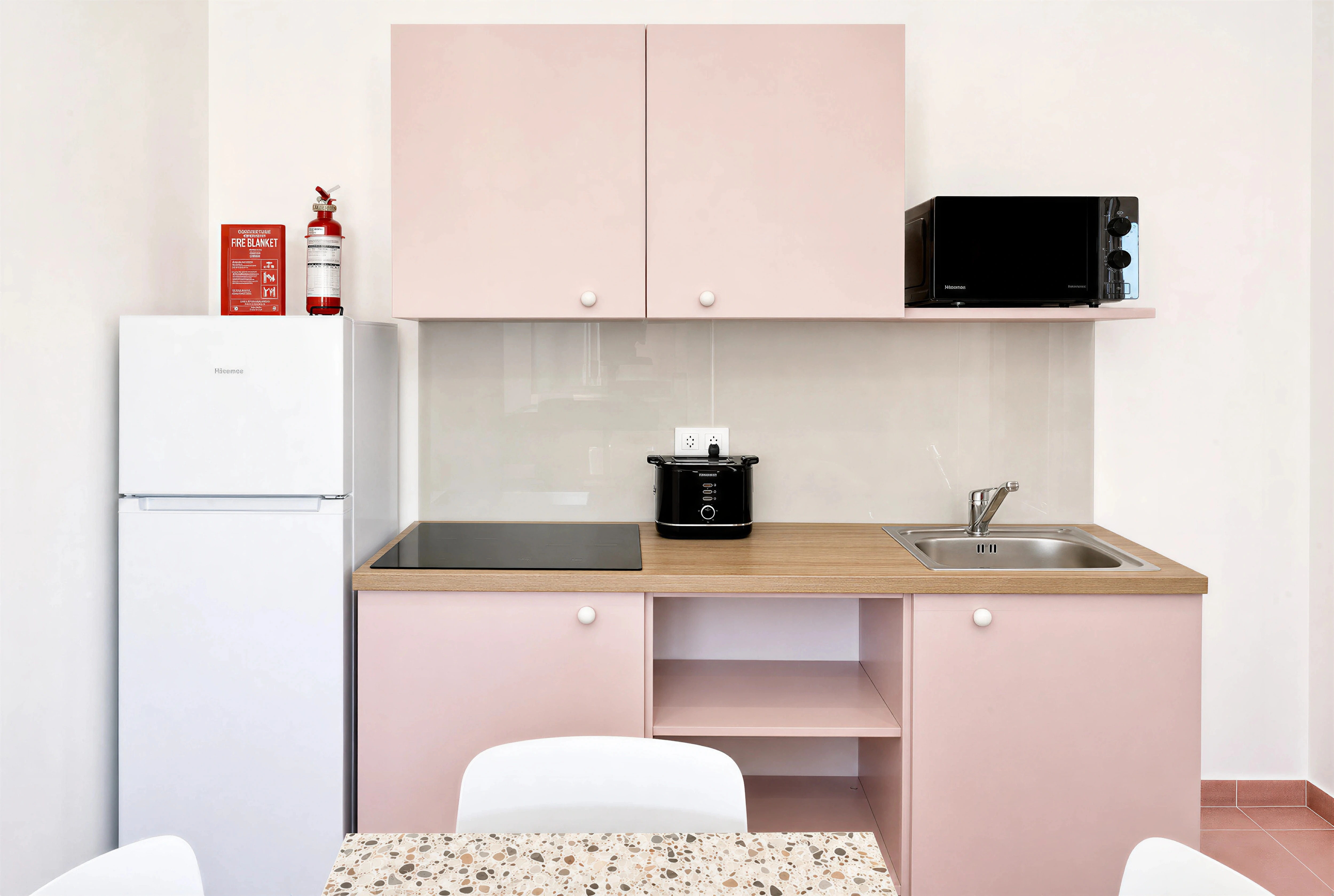 Pink kitchen with induction hob, fridge and terrazzo dining table at Flamingo Apartments Paceville