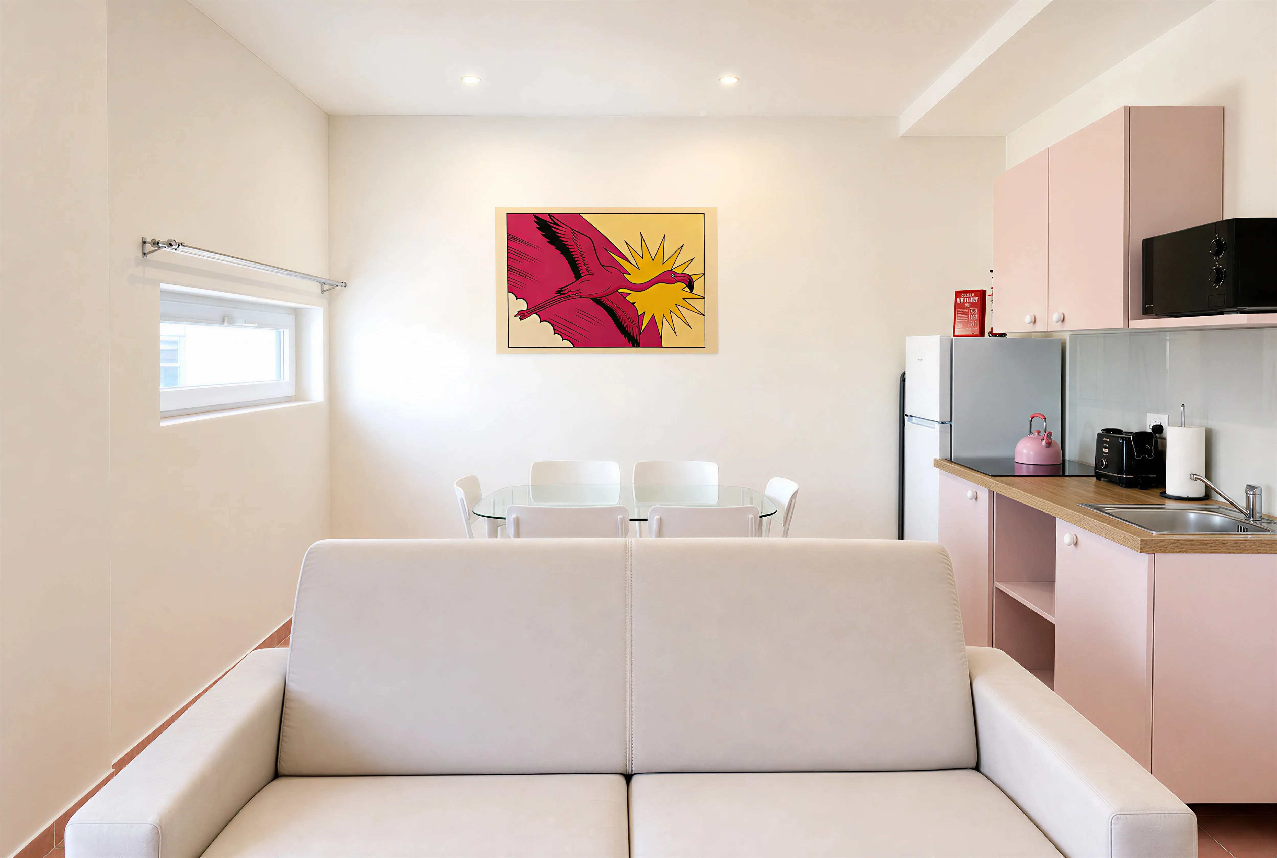 Open-plan living area with cream sofa, dining table and pink kitchen